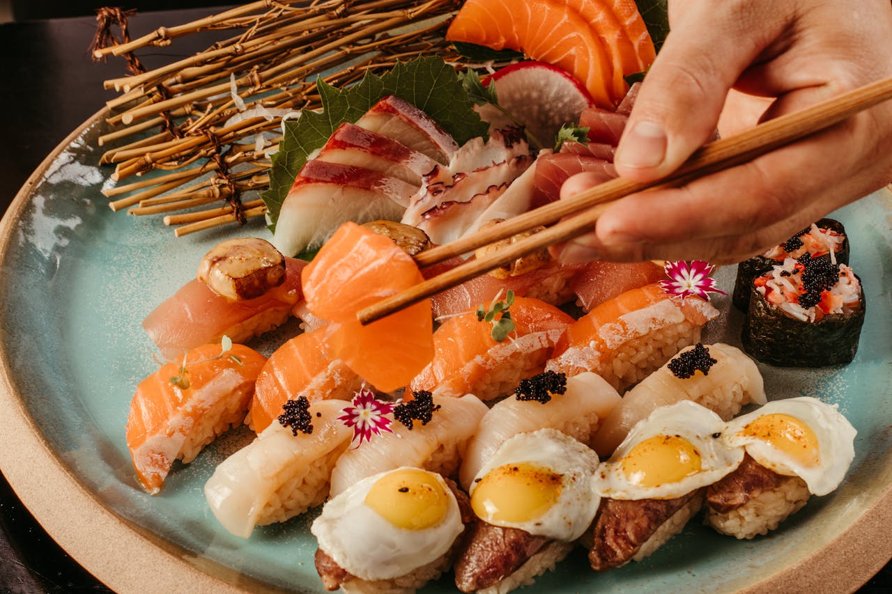 Sushi plate with a hand grabbing a piece of shashimi.